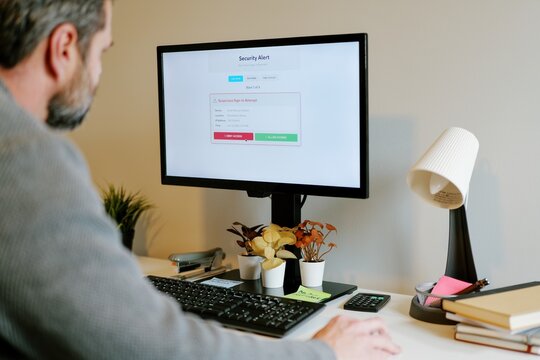 Middle Aged Man Gets Barrage of Internet of Things Smart Home Alerts While Working from Home in Remote Office - IoT Cybersecurity Concept