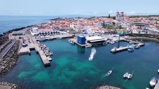AZORES - 11.3.2025 - Very good aerial view of a motorboat pulling away from a waterfront parish on the Azores' Terceira Island.