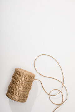 Spool of natural twine on white surface