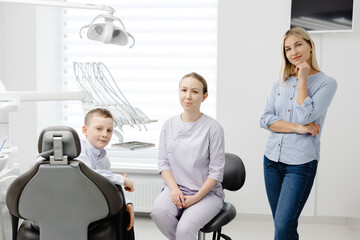 Dentist explaining dental hygiene to mother and child in clinic
