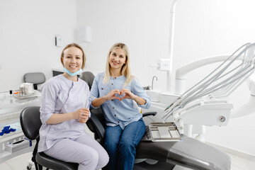 Dentist and patient making heart shape with hands in dental clinic