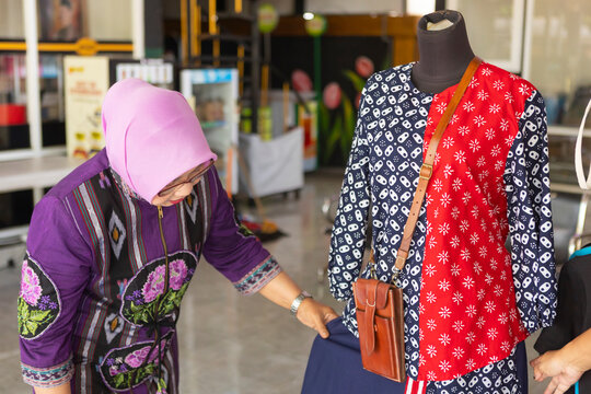 Woman viewing batik clothing in shop setting