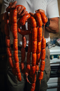 Man holding chorizo sausages in a traditional setting