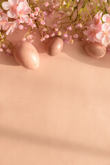 Speckled Easter Eggs and Cherry Blossoms on Peach Background. Festive Spring Flatlay