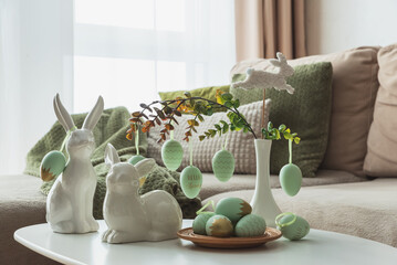 Cozy Easter Living Room Decor with Bunny Figurines and Hanging Eggs on White Table