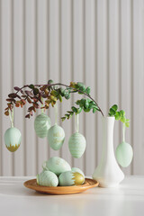 Hanging Easter Eggs and Spring Branches in Vase. Festive Pastel Decor