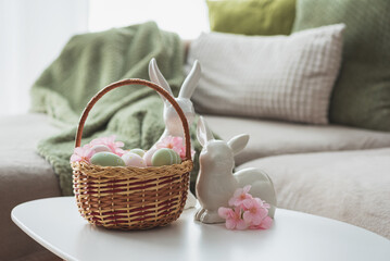 Easter Basket with Ester Eggs,  Plush Bunny and Spring Decor on White Table intoCozy Living Room