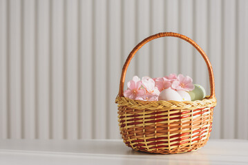 Wicker Easter Basket with Pastel Eggs and Flowers. Soft Spring Decor
