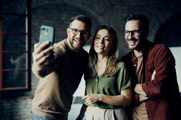 Cheerful business team posing for a smartphone photo during a break, showing positive corporate culture and friendship

