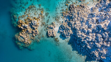 Vertical drone footage of white travertine-like rocks and the shallow lake bed in turquoise waters. The unique texture and color contrast created by nature.