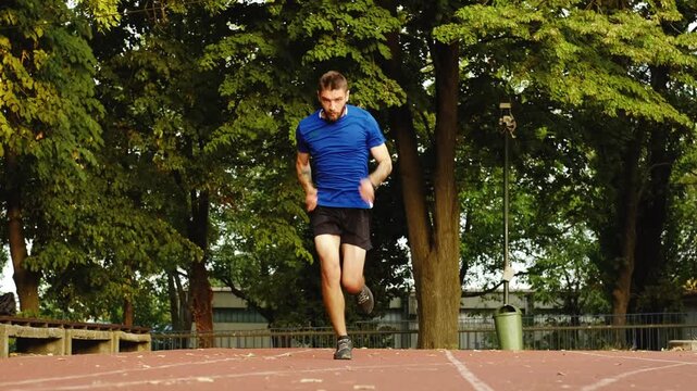 A man in sportswear leans forward and launches into a sprint from the starting position on the stadium track. The scene conveys speed, determination, and dynamic athletic movement