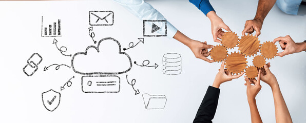 Hands of diverse team members gathered around a table, symbolizing collaboration and innovation in cloud technology with a digital graphic overlay of various icons. Trope