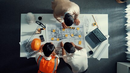 Top down aerial view of smart architect engineer team pointing and discussing about building construction. Group of diverse people working together to plan and design by using blueprint. Alimentation. © InfiniteFlow