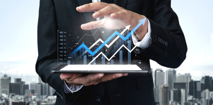 A businessman stands with a digital tablet showcasing visual graphs that depict financial growth and trends against a city skyline, symbolizing modern business success. Scalp - Powered by Adobe