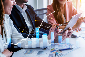 A business team engages in financial analysis while utilizing data visualizations on a tablet, showcasing collaboration in a modern office environment. Scalp