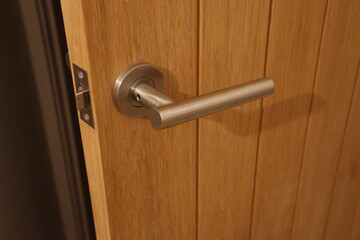 Obraz premium A door handle is shown in a wooden door
