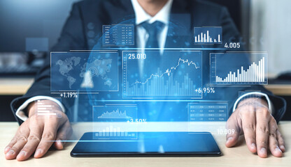 Businessman in formal attire analyzes financial data on a tablet, surrounded by virtual graphs and charts, in a modern office setting depicting future technology applications. Scalp