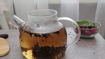 Process brewing tea, tea ceremony, Cup of freshly brewed fruit herbal tea, dark mood. Hot water is...