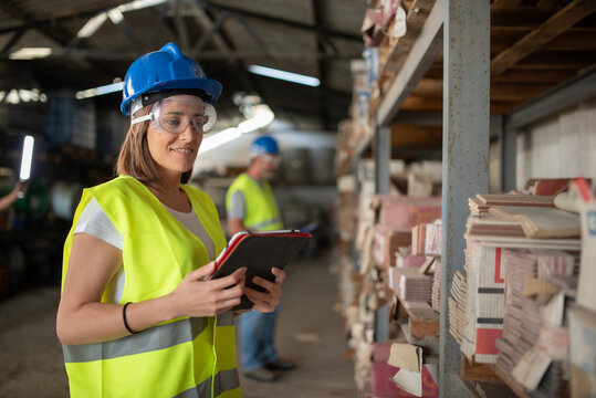 Woman Working in a Warehouse Doing Construction Material Inventory Wearing Helmet and Reflective Vest