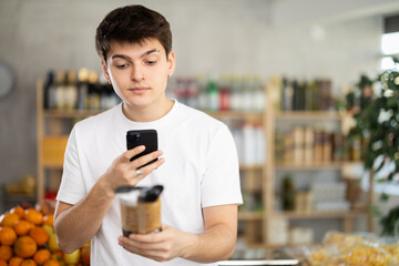 Tech-savvy young shopper scanning spaghetti package with smartphone, using mobile app to quickly...