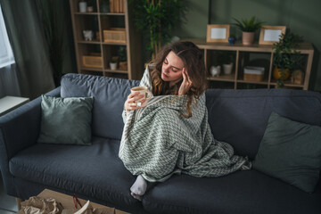Woman enjoying comfortable morning tea on sofa at home