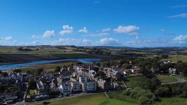 Aerial drone view of the village of Alnmouth in Northumberland showing buildings and roads along the river Aln and surrounding countryside