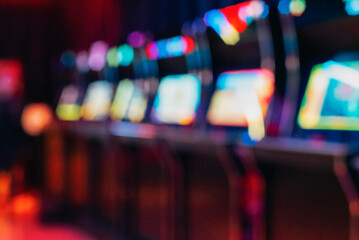 Blurred row of vintage arcade machines with colorful illuminated screens, background © Viktoriya