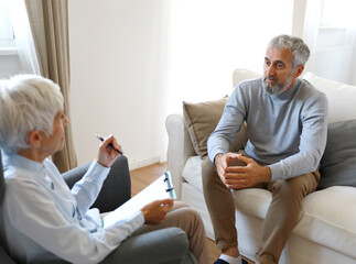 Portrait of a senior mature or mid aged man looking thoughtful or stressed and sad while sitting in session with his female therapist