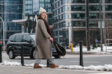 Winter city wanderlust: female tourist walking historic Warsaw old town, pastel facades and holiday lights, cozy coat, scarf and beanie. Urban sightseeing, slow travel, sustainable Europe escape eco.