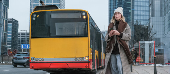 Winter city wanderlust: female tourist walking historic Warsaw old town, pastel facades and holiday lights, cozy coat, scarf and beanie. Urban sightseeing, slow travel, sustainable Europe escape eco.