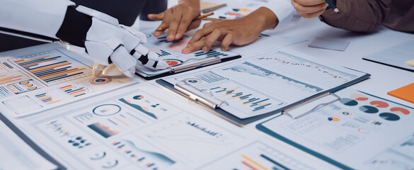 A collaborative office scene featuring human hands working alongside a robotic arm, highlighting data analysis and innovative technology in a productive environment.Noogenesis