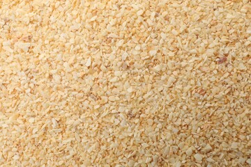 Granulated dried garlic as background, top view