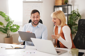 Two team members actively discuss ideas in a bright office. They use digital devices to exchange thoughts. Their expressions show excitement and engagement with the project.