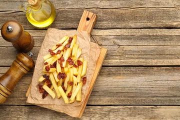 Fototapete Zu Essen Delicious French fries with bacon served on wooden table, flat lay. Space for text  © New Africa