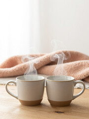 Cozy romantic card concept: two ceramic mugs with steam forming a heart shape