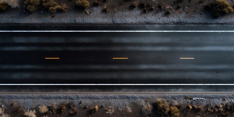 Top down view of dark wet asphalt road featuring clear white edge lines and subtle yellow center dashes, concept for travel imagery, infrastructure background and car transportation concepts