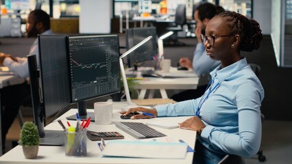 Day trader analyzes stock market price charts, taking notes to make informed buy and sell decisions. Stockbroker writing down analysis insights, placing orders using trading platform