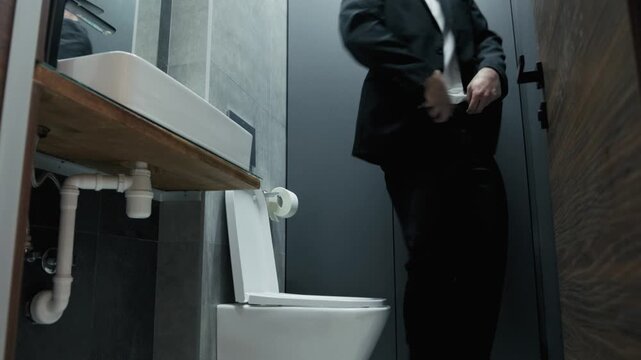 A businessman experiences discomfort and indigestion while working in a modern office. A business man with a tense expression sits on the toilet, suffering from diarrhea and abdominal pain.