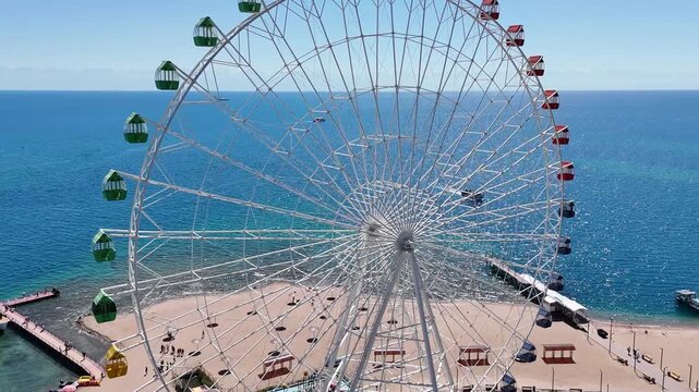 Ferris wheel by Issyk-Kul Lake with scenic mountains in the background, a popular tourist spot.