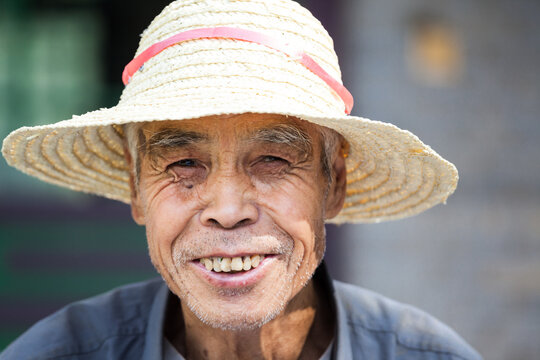 Portrait of Elderly Chinese Man in Straw Hat Smiling, China