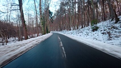 Obraz premium Car Driving Through Scenic Winter Forest Down Narrow Road Covered Fresh Snow