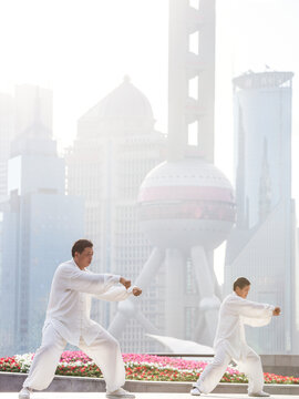 Chinese people practicing Tai Chi with skyline in the background, Shanghai, China