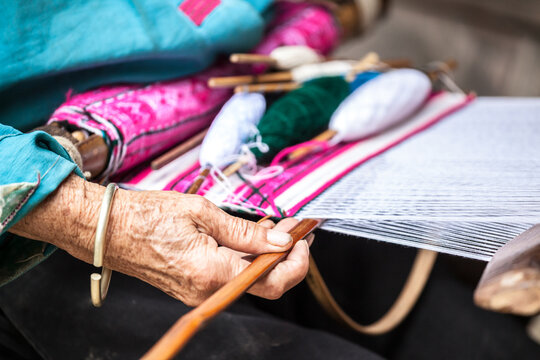 Close Up View of elderly woman hand and Embroidered Textile Threading Patterns on Ethnic Robe, China