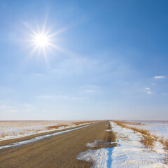 long asphalt road among winter snowbound at the sunny day