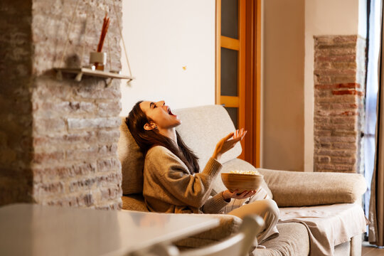 Woman enjoying playful moment eating popcorn at home