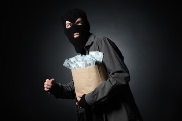 Thief with paper bag full of money on black gradient background