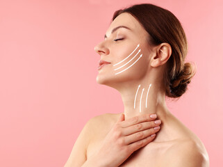 Beautiful woman with lifting lines on face and neck against pink background. Skin care for...