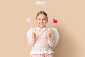 Naklejka premium Cute little girl dressed as cupid with hearts on beige background. Valentine's Day celebration
