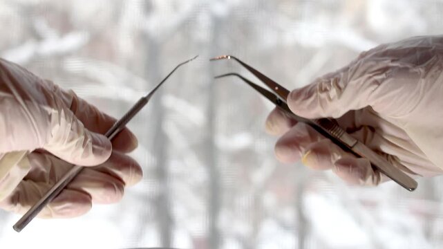 Hands performing precise surgical operation with medical instruments in dark room