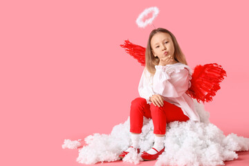 Fototapeta premium Cute little girl dressed as cupid sitting on cloud against pink background. Valentine's Day celebration